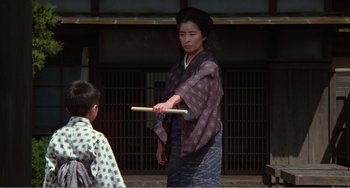 Movie still from “Dreams” (1990), directed by Akira Kurosawa – A woman holding a wooden stick in front of a boy; Medium shot, Over the shoulder angle