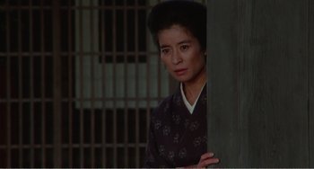 Movie still from “Dreams” (1990), directed by Akira Kurosawa – A woman standing in front of a metal gate; Medium shot, Low angle