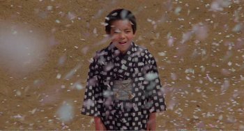 Movie still from “Dreams” (1990), directed by Akira Kurosawa – A young boy standing in front of a bunch of falling petals; Medium shot, High angle