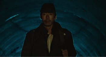 Movie still from “Dreams” (1990), directed by Akira Kurosawa – A man with a hat is holding a knife in his hand; Medium shot, Low angle