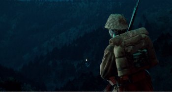 Movie still from “Dreams” (1990), directed by Akira Kurosawa – A person wearing a hat and holding a rifle; Wide shot, Low angle