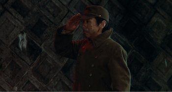 Movie still from “Dreams” (1990), directed by Akira Kurosawa – A man in a military uniform saluting in front of a brick wall; Medium shot, Low angle