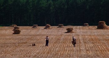 Movie still from “Dreams” (1990), directed by Akira Kurosawa – Two people in a field with a camera; Extreme Wide shot, High angle