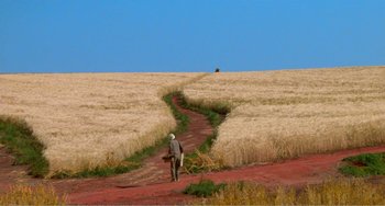 Movie still from “Dreams” (1990), directed by Akira Kurosawa – A man walking down a dirt path through a field; Extreme Wide shot, High angle