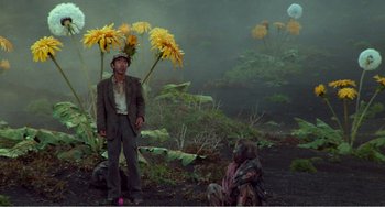 Movie still from “Dreams” (1990), directed by Akira Kurosawa – A man standing next to a woman with yellow flowers in her hair; Wide shot, Low angle