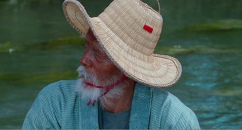 An older man wearing a straw hat and a blue robe
