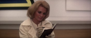 Movie still from “Dressed to Kill” (1980), directed by Brian De Palma – A woman in a white coat holding a notebook; Close Up shot, Over the shoulder angle