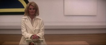 Movie still from “Dressed to Kill” (1980), directed by Brian De Palma – A woman sitting on the ground holding a stack of money; Medium shot, Low angle