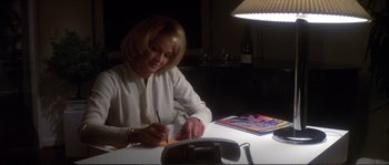 Movie still from “Dressed to Kill” (1980), directed by Brian De Palma – A woman sitting at a table writing on a piece of paper; Medium shot, High angle
