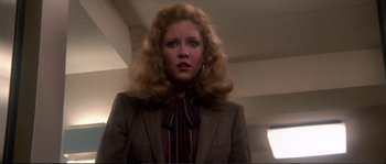 Movie still from “Dressed to Kill” (1980), directed by Brian De Palma – A woman with blonde hair wearing a jacket and a tie; Close Up shot, Low angle
