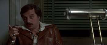 Movie still from “Dressed to Kill” (1980), directed by Brian De Palma – A man wearing a brown leather jacket and a white shirt; Close Up shot, High angle