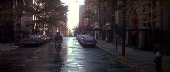 Movie still from “Dressed to Kill” (1980), directed by Brian De Palma – A man riding a bike down a street next to parked cars; Extreme Wide shot, High angle
