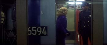 Movie still from “Dressed to Kill” (1980), directed by Brian De Palma – A woman standing in front of a train window; Wide shot, Over the shoulder angle
