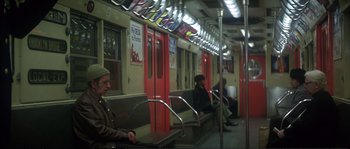 Movie still from “Dressed to Kill” (1980), directed by Brian De Palma – People are sitting on a subway train in a train station; Wide shot, High angle