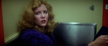Movie still from “Dressed to Kill” (1980), directed by Brian De Palma – A woman with blonde hair sitting in front of a computer monitor; Close Up shot, Low angle