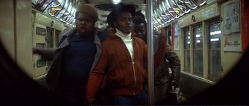 Movie still from “Dressed to Kill” (1980), directed by Brian De Palma – A group of people riding on a subway train; Medium shot, Low angle