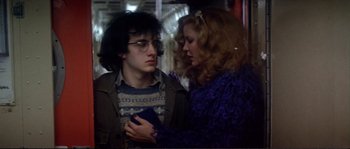 Movie still from “Dressed to Kill” (1980), directed by Brian De Palma – A man and a woman standing next to each other on a train; Medium shot, Low angle