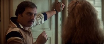 Movie still from “Dressed to Kill” (1980), directed by Brian De Palma – A man holding onto a curtain while a woman looks on; Close Up shot, Over the shoulder angle
