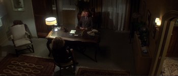 Movie still from “Dressed to Kill” (1980), directed by Brian De Palma – A man sitting at a desk in a dark room; Wide shot, High angle