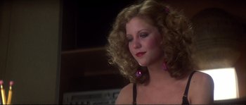 Movie still from “Dressed to Kill” (1980), directed by Brian De Palma – A woman with long blonde curly hair wearing a black top; Close Up shot, Low angle