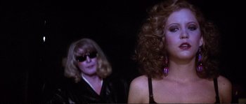 Movie still from “Dressed to Kill” (1980), directed by Brian De Palma – A woman with long curly red hair wearing sunglasses and a leather jacket; Close Up shot, Over the shoulder angle