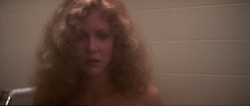 Movie still from “Dressed to Kill” (1980), directed by Brian De Palma – A woman with curly blonde hair in a bathroom; Close Up shot, Low angle