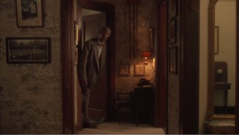 Movie still from “Driving Miss Daisy” (1989), directed by Bruce Beresford – A man in a suit and bow tie standing in a doorway; Wide shot, High angle