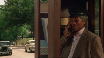 Movie still from “Driving Miss Daisy” (1989), directed by Bruce Beresford – A man talking on a phone next to a car; Medium shot, Low angle