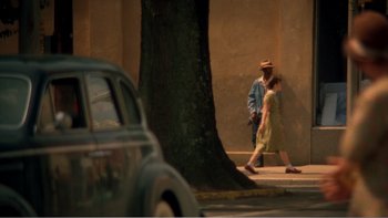 Movie still from “Driving Miss Daisy” (1989), directed by Bruce Beresford – Two people walking down the sidewalk next to a tree; Extreme Wide shot, High angle