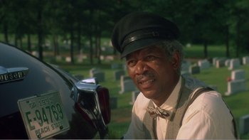 Movie still from “Driving Miss Daisy” (1989), directed by Bruce Beresford – An older man wearing a hat sitting next to a motorcycle; Close Up shot, Over the shoulder angle
