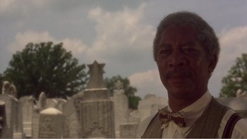 Movie still from “Driving Miss Daisy” (1989), directed by Bruce Beresford – An older man standing in front of a cemetery; Close Up shot, Low angle