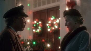 Movie still from “Driving Miss Daisy” (1989), directed by Bruce Beresford – A man and a woman standing next to each other in front of christmas lights; Close Up shot, Low angle