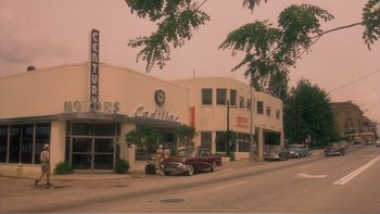 Movie still from “Driving Miss Daisy” (1989), directed by Bruce Beresford – An old car parked on the side of the street; Extreme Wide shot, High angle