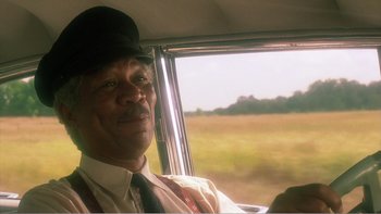 Movie still from “Driving Miss Daisy” (1989), directed by Bruce Beresford – A man sitting in the driver's seat of a car; Close Up shot, Low angle