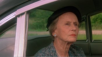 Movie still from “Driving Miss Daisy” (1989), directed by Bruce Beresford – An older woman sitting in the back seat of a car; Close Up shot, Over the shoulder angle
