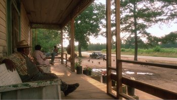 Movie still from “Driving Miss Daisy” (1989), directed by Bruce Beresford – People are sitting on the porch of a house; Extreme Wide shot, Low angle