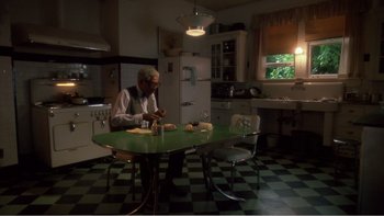 Movie still from “Driving Miss Daisy” (1989), directed by Bruce Beresford – An older man sitting at a table in a kitchen; Wide shot, High angle
