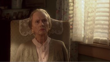 Movie still from “Driving Miss Daisy” (1989), directed by Bruce Beresford – An older woman sitting in a chair in front of a window; Close Up shot, High angle