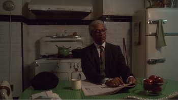 Movie still from “Driving Miss Daisy” (1989), directed by Bruce Beresford – An older man sitting at a table reading a newspaper; Medium shot, Low angle