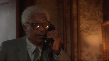 Movie still from “Driving Miss Daisy” (1989), directed by Bruce Beresford – An older man talking on a phone while wearing glasses; Close Up shot, Low angle