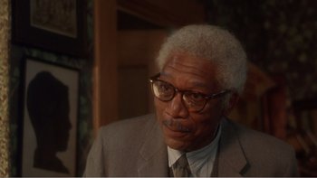 Movie still from “Driving Miss Daisy” (1989), directed by Bruce Beresford – An older man wearing a suit and glasses; Close Up shot, Over the shoulder angle