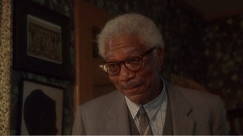 Movie still from “Driving Miss Daisy” (1989), directed by Bruce Beresford – An older man wearing a suit and glasses; Close Up shot, Over the shoulder angle