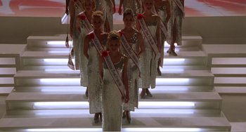 Movie still from “Drop Dead Gorgeous” (1999), directed by Michael Patrick Jann – A group of young women in silver dresses holding red ribbons; Extreme Wide shot, Low angle