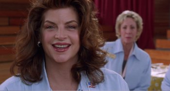 Movie still from “Drop Dead Gorgeous” (1999), directed by Michael Patrick Jann – A woman with long curly hair smiles at the camera while another woman looks on; Close Up shot, Low angle