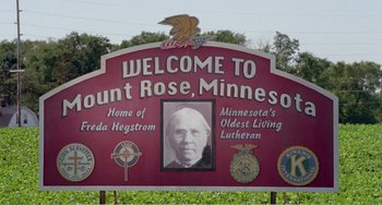 Movie still from “Drop Dead Gorgeous” (1999), directed by Michael Patrick Jann – A red sign with a picture of a person on it; Extreme Wide shot, High angle