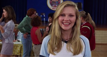 Movie still from “Drop Dead Gorgeous” (1999), directed by Michael Patrick Jann – A woman smiles for the camera at an event; Medium shot, Low angle