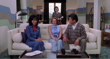 Movie still from “Drop Dead Gorgeous” (1999), directed by Michael Patrick Jann – A group of people sitting on top of a white couch; Medium shot, Over the shoulder angle