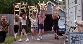 Movie still from “Drop Dead Gorgeous” (1999), directed by Michael Patrick Jann – A group of people holding chairs up in the air; Wide shot, High angle