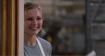 Movie still from “Drop Dead Gorgeous” (1999), directed by Michael Patrick Jann – A woman smiling for the camera in a kitchen; Close Up shot, Over the shoulder angle