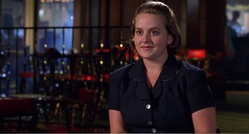 Movie still from “Drop Dead Gorgeous” (1999), directed by Michael Patrick Jann – A woman in a black shirt is sitting in front of a chair; Close Up shot, Over the shoulder angle